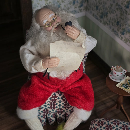 Vintage-style Santa Claus figure in a room with floral wallpaper and small table.