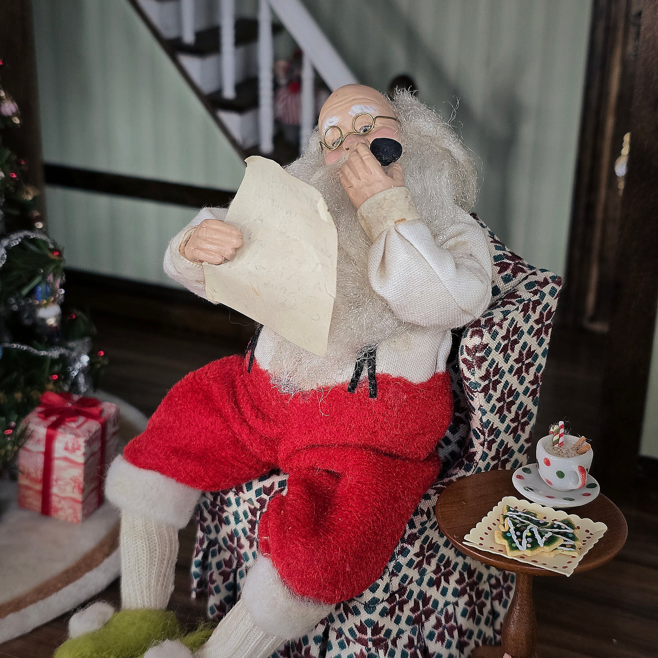 Santa Claus doll in a festive setting with a Christmas tree and presents.