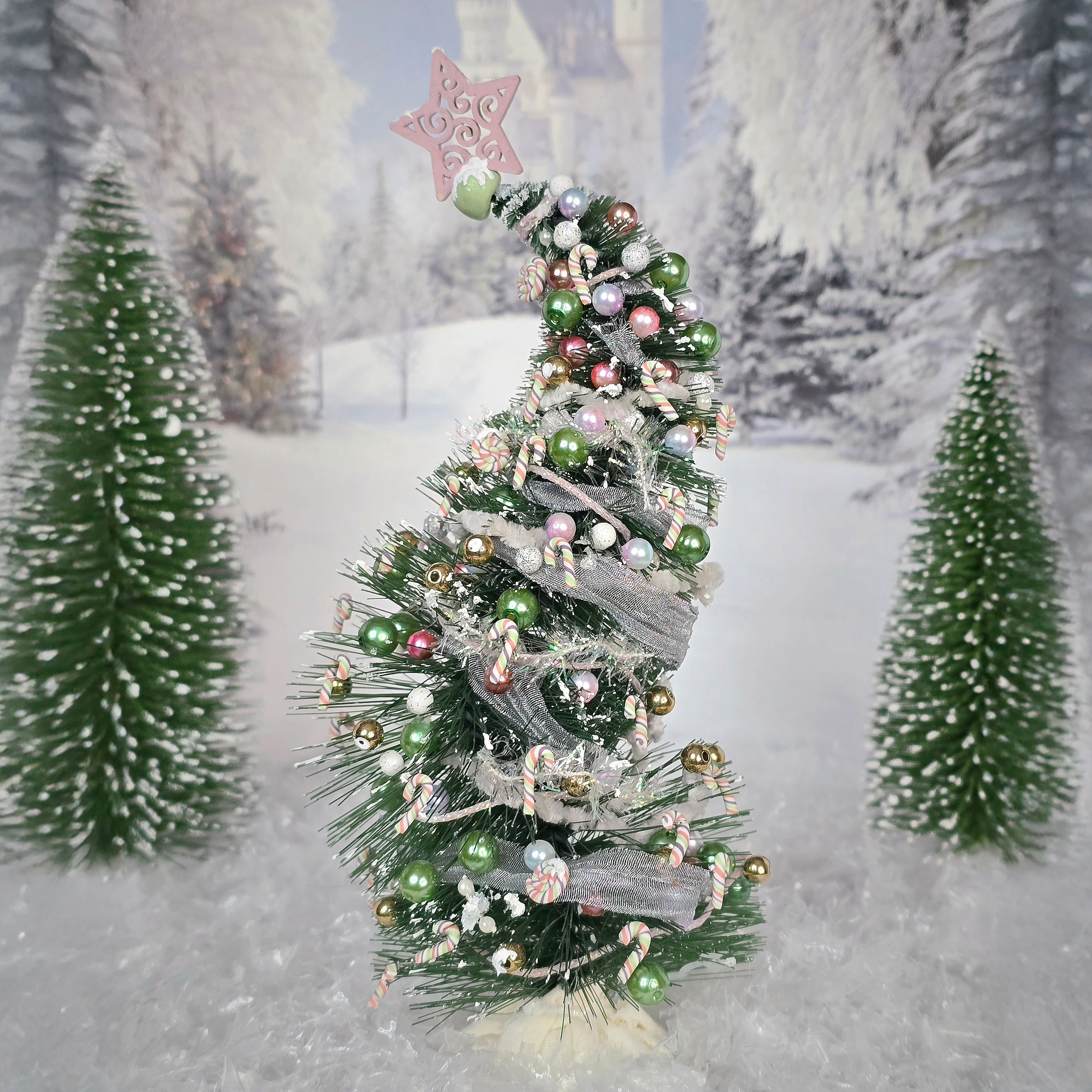 Decorated Christmas tree with green and gold ornaments against a snowy forest background