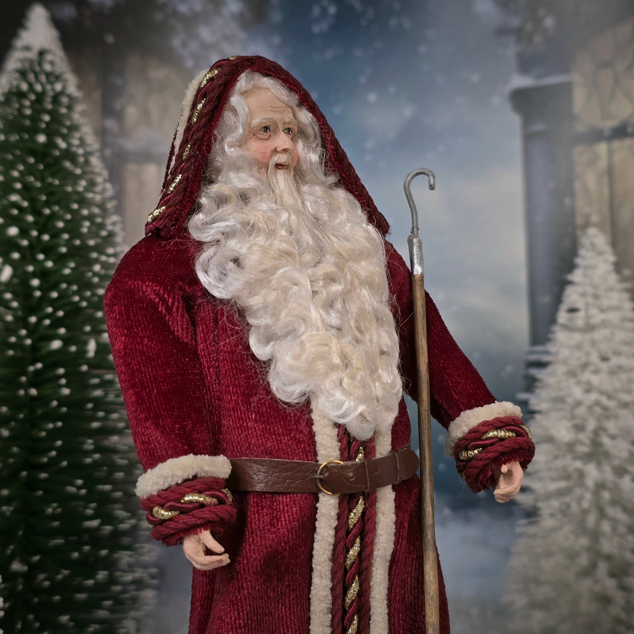 Santa Claus doll with a long white beard and red coat in a snowy scene.