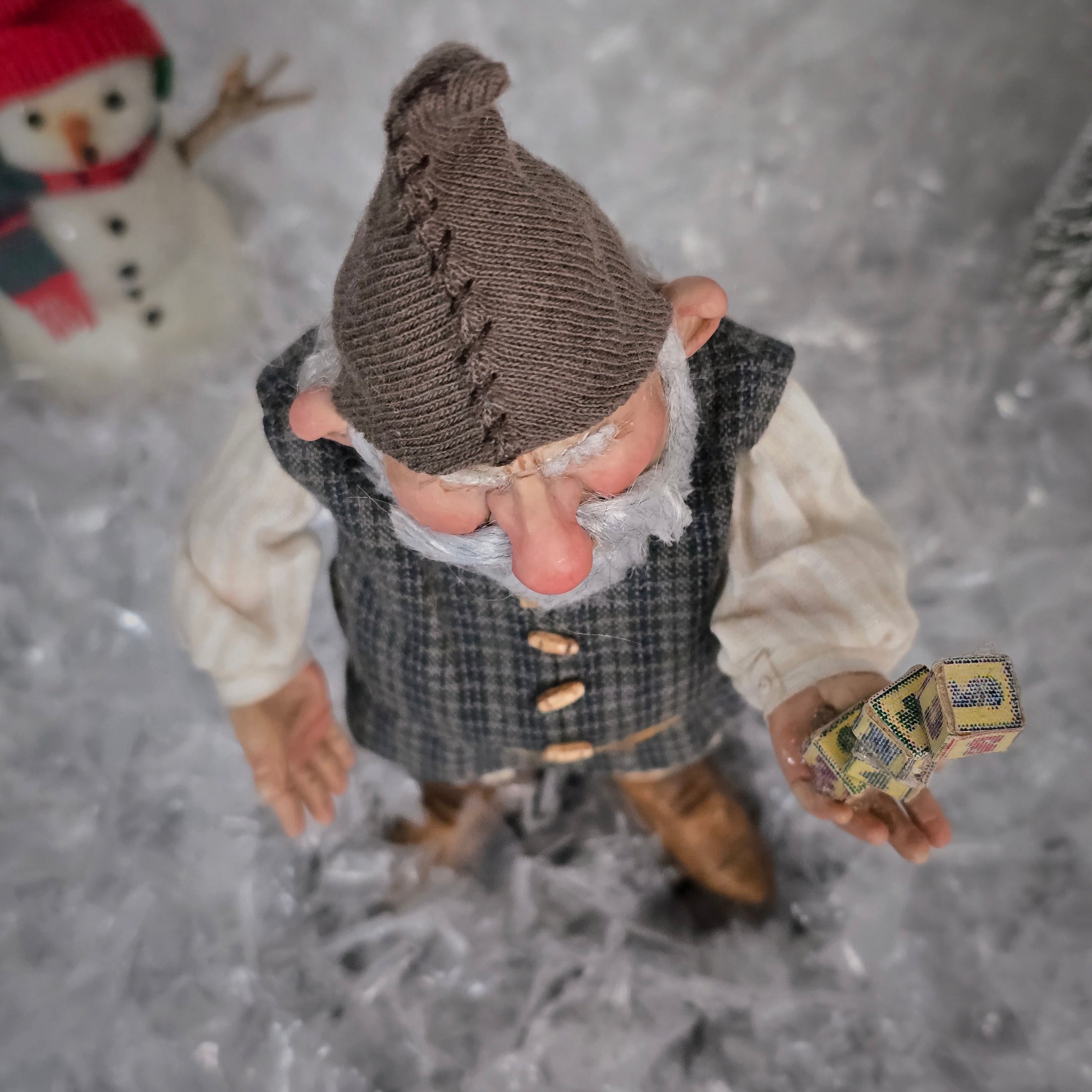 Sharon Cariola Elf dollhouse doll  holding blocks with a snowman in the background