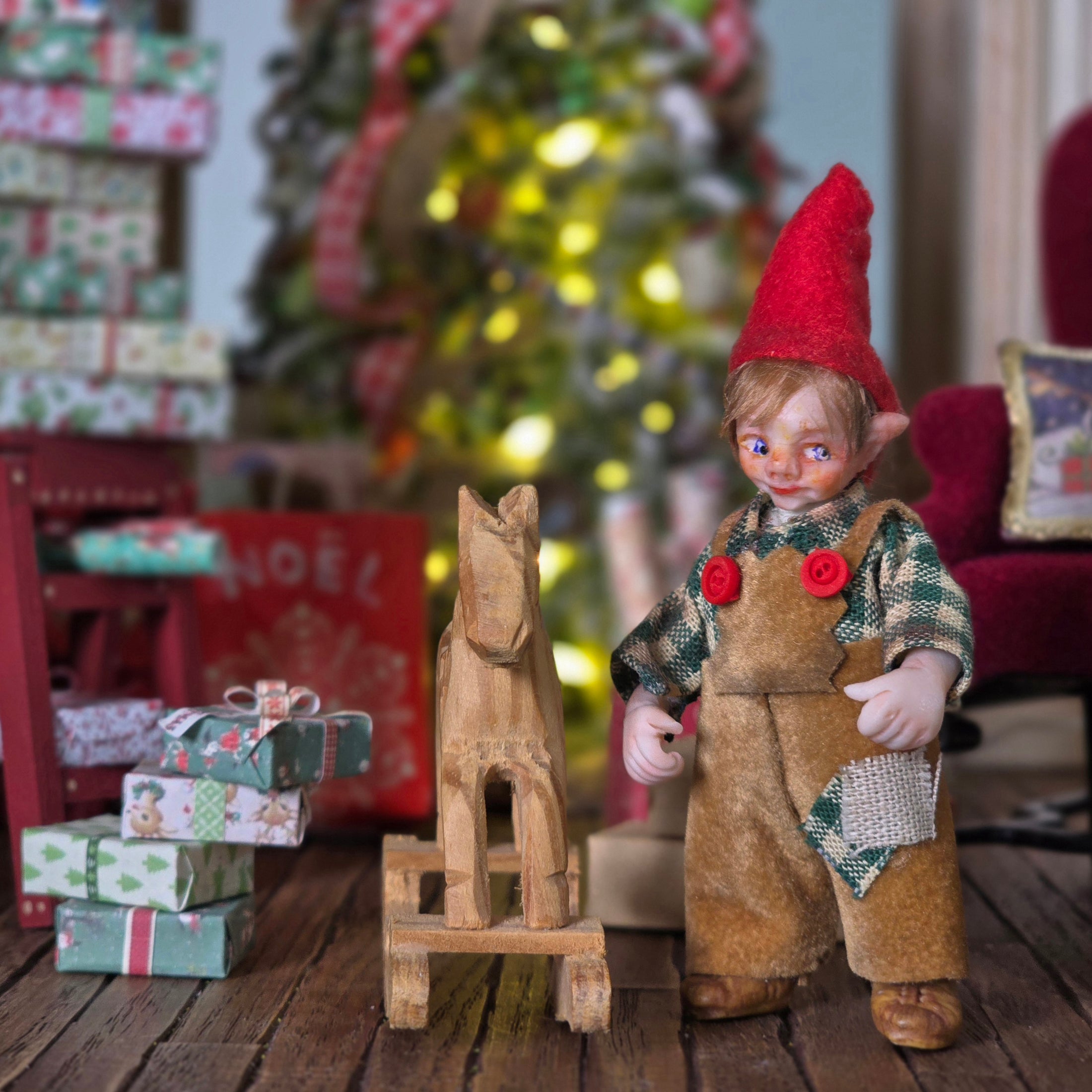 Clay elf character with a wooden horse in a festive setting with Christmas tree and presents.