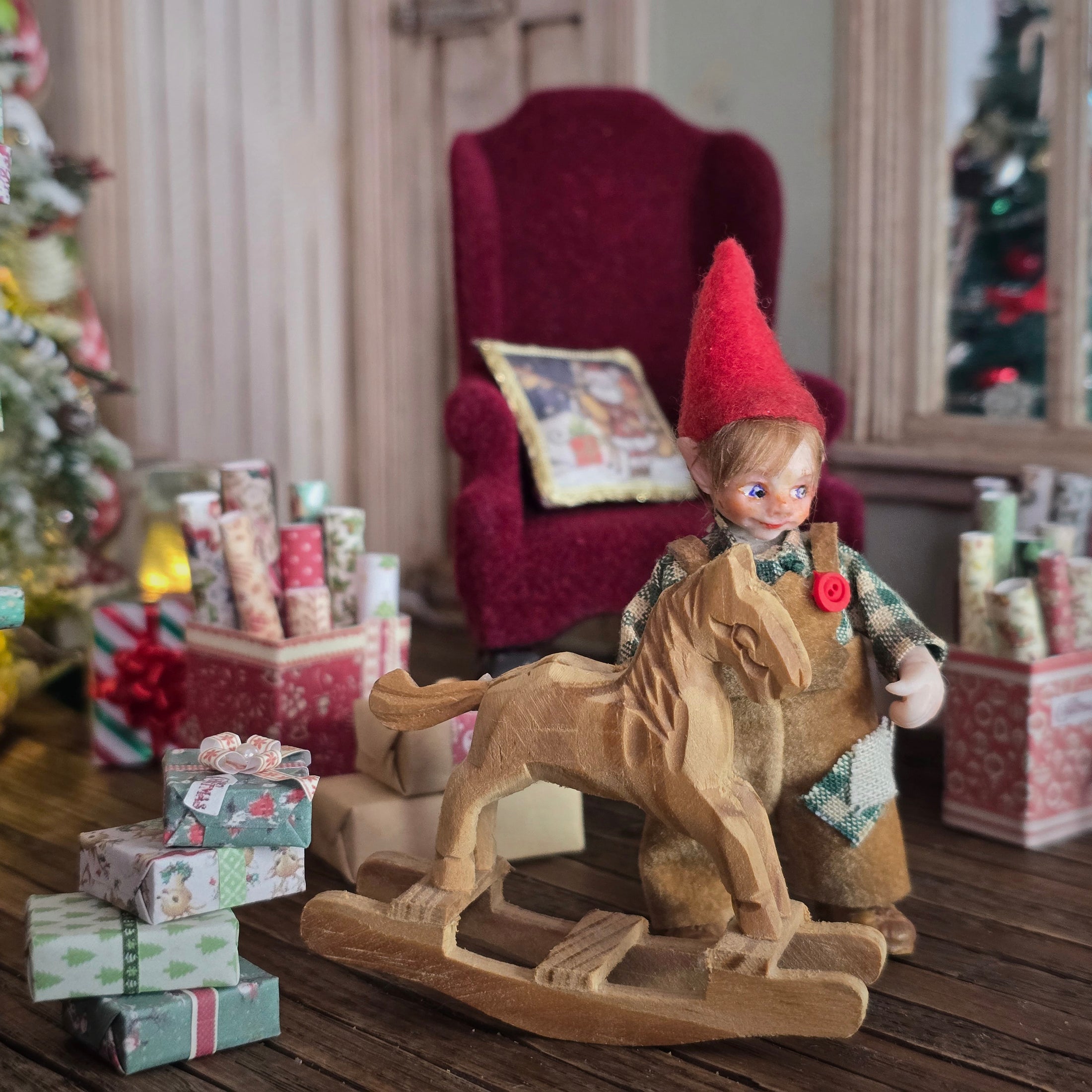 Clay elf character on a rocking horse with Christmas decorations in the background