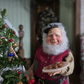 Load image into Gallery viewer, Old Christmas Elf doll with a beard holding cookies next to a decorated Christmas tree.
