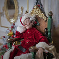 Load image into Gallery viewer, Santa dollhouse doll in a red outfit with white fur trim, sitting on an ornate chair in a festive setting.
