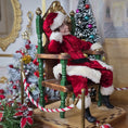 Load image into Gallery viewer, Santa dollhouse doll sitting on a chair in a festive room with Christmas trees.
