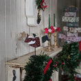 Load image into Gallery viewer, Decorative Christmas scene with a  flying santa figure, ornaments, and candles on a rustic shelf.

