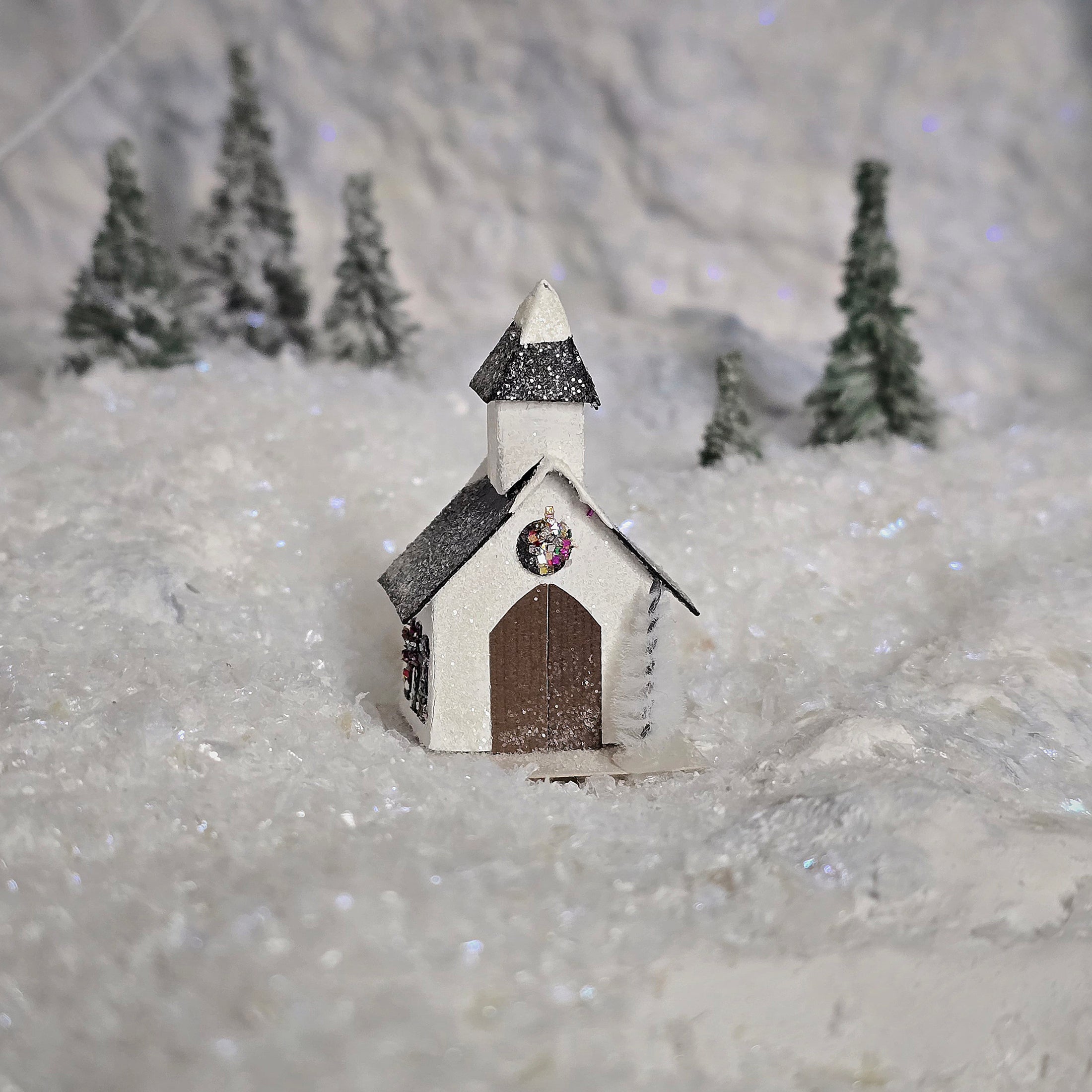 Small model of a church in a snowy landscape with trees in the background