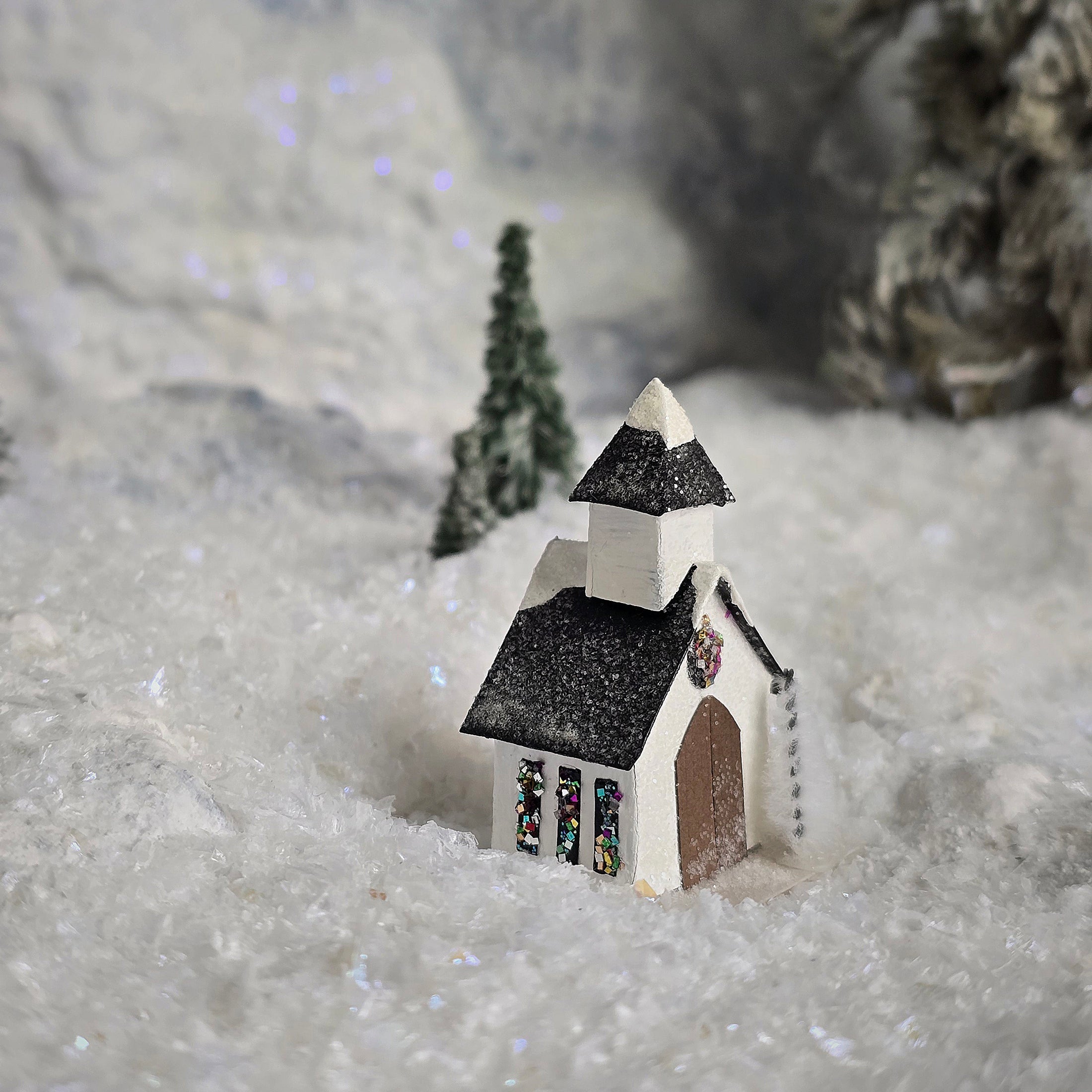 Small model of a church with a steeple on a snowy surface