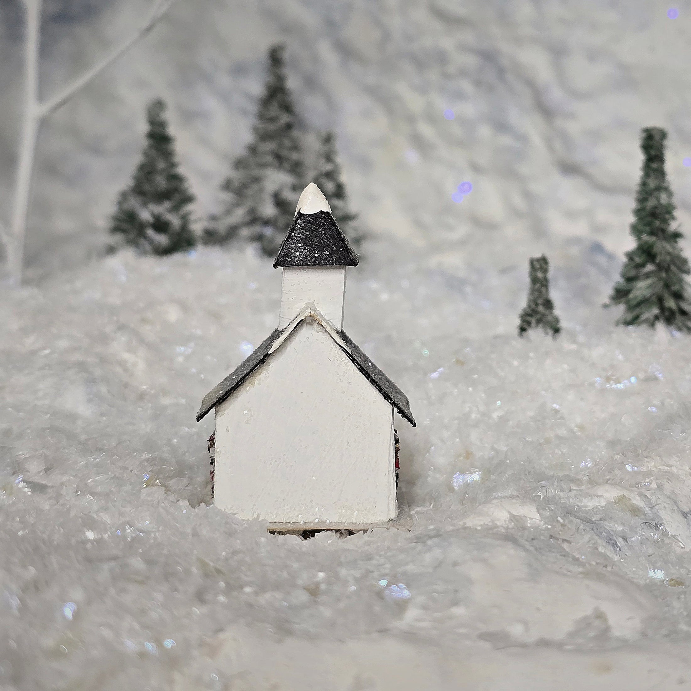 Small model of a church in a snowy landscape with trees in the background