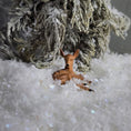 Load image into Gallery viewer, Small deer figurine in a snowy landscape with a textured branch above
