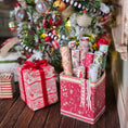 Load image into Gallery viewer, Decorative Christmas scene with wrapped presents and a tree in the background
