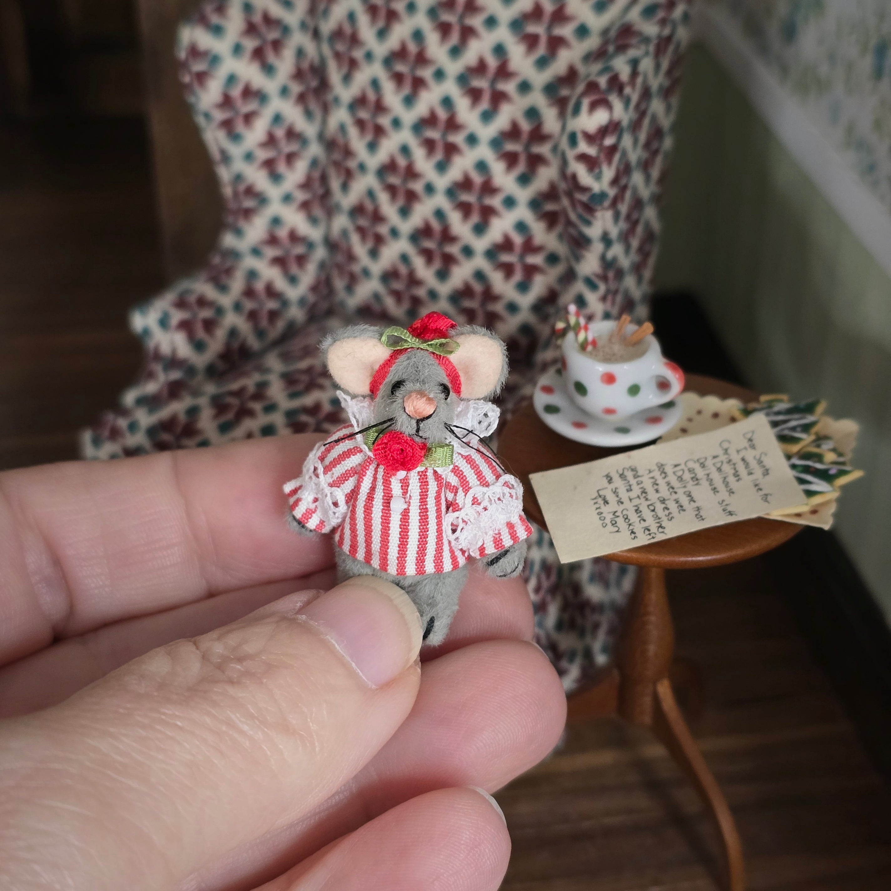 Small decorative mouse figure held in a hand with a blurred background