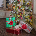 Load image into Gallery viewer, Decorated Christmas tree with ornaments and presents on a wooden floor.
