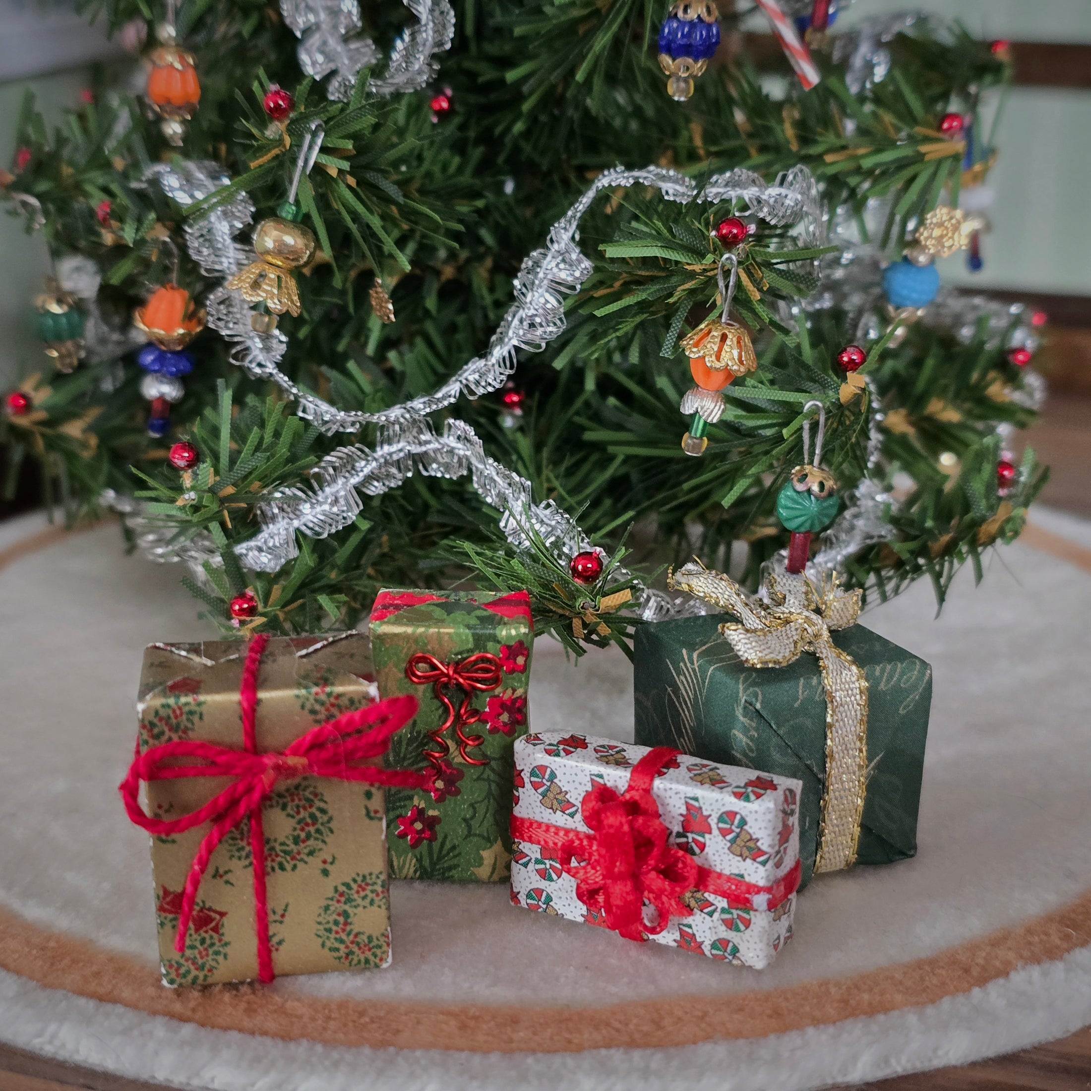 Decorative Christmas scene with small gift boxes and a tree in the background.