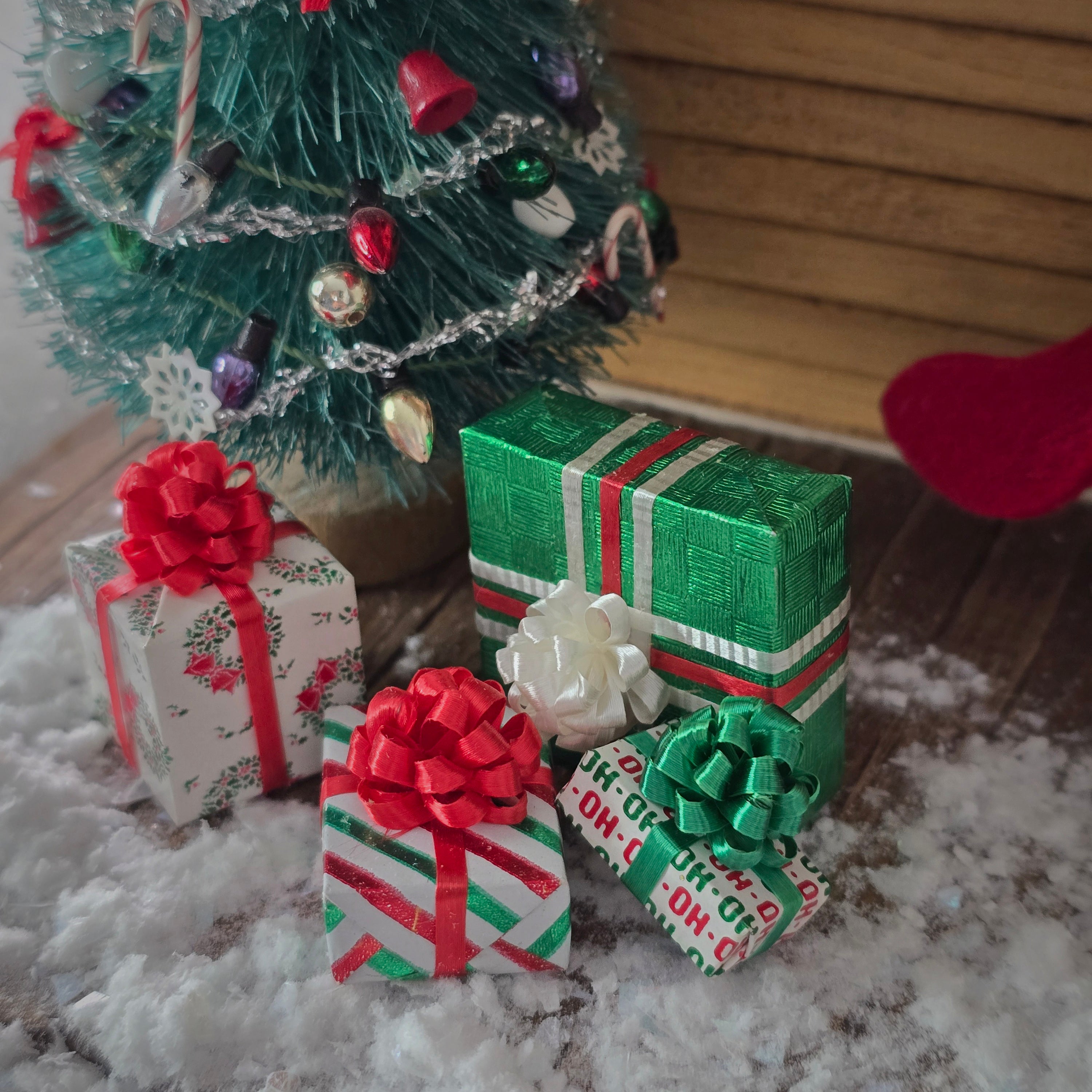 Decorative Christmas scene with a small tree and wrapped presents on a snowy surface.