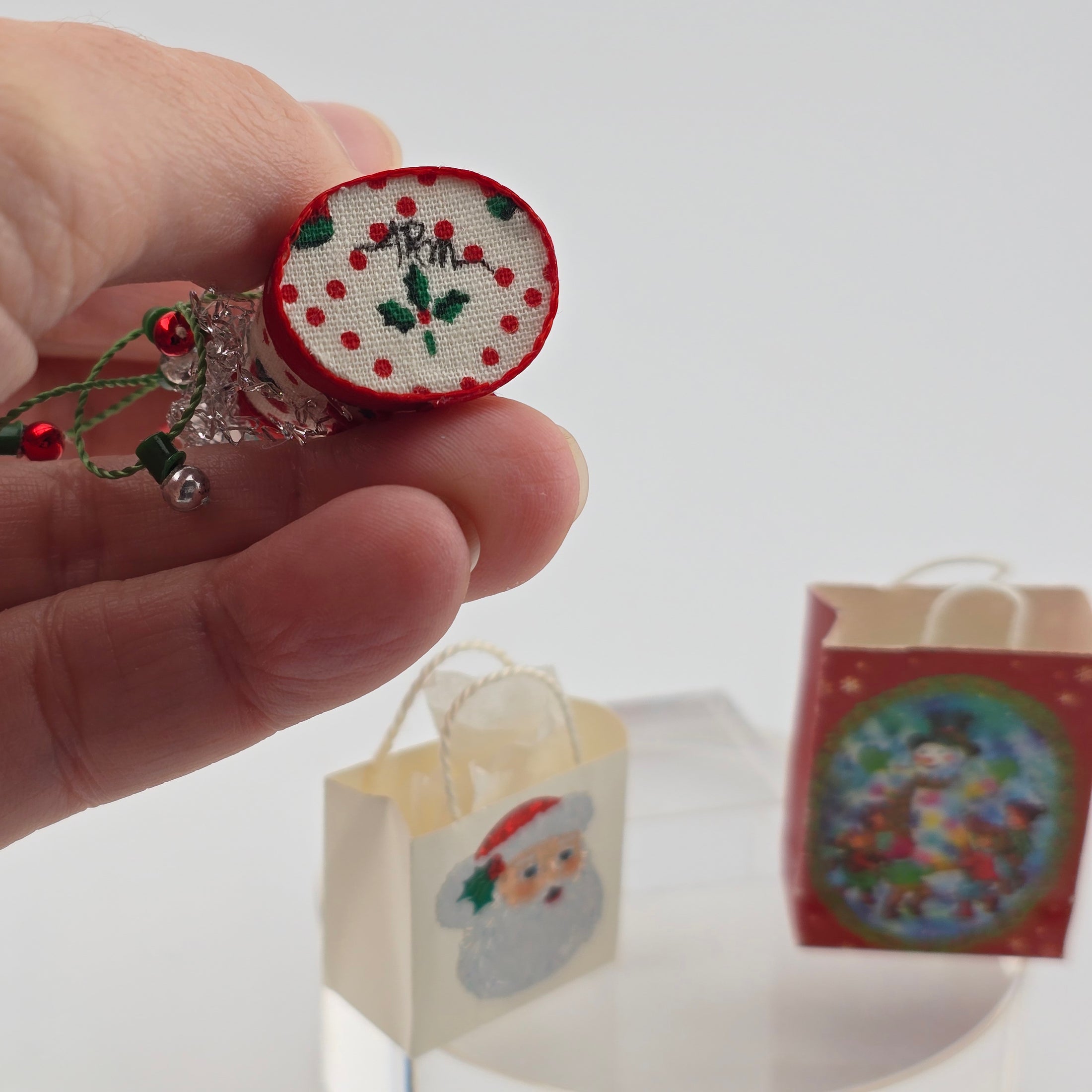 Hand holding a small embroidered clock with decorative elements on a white background