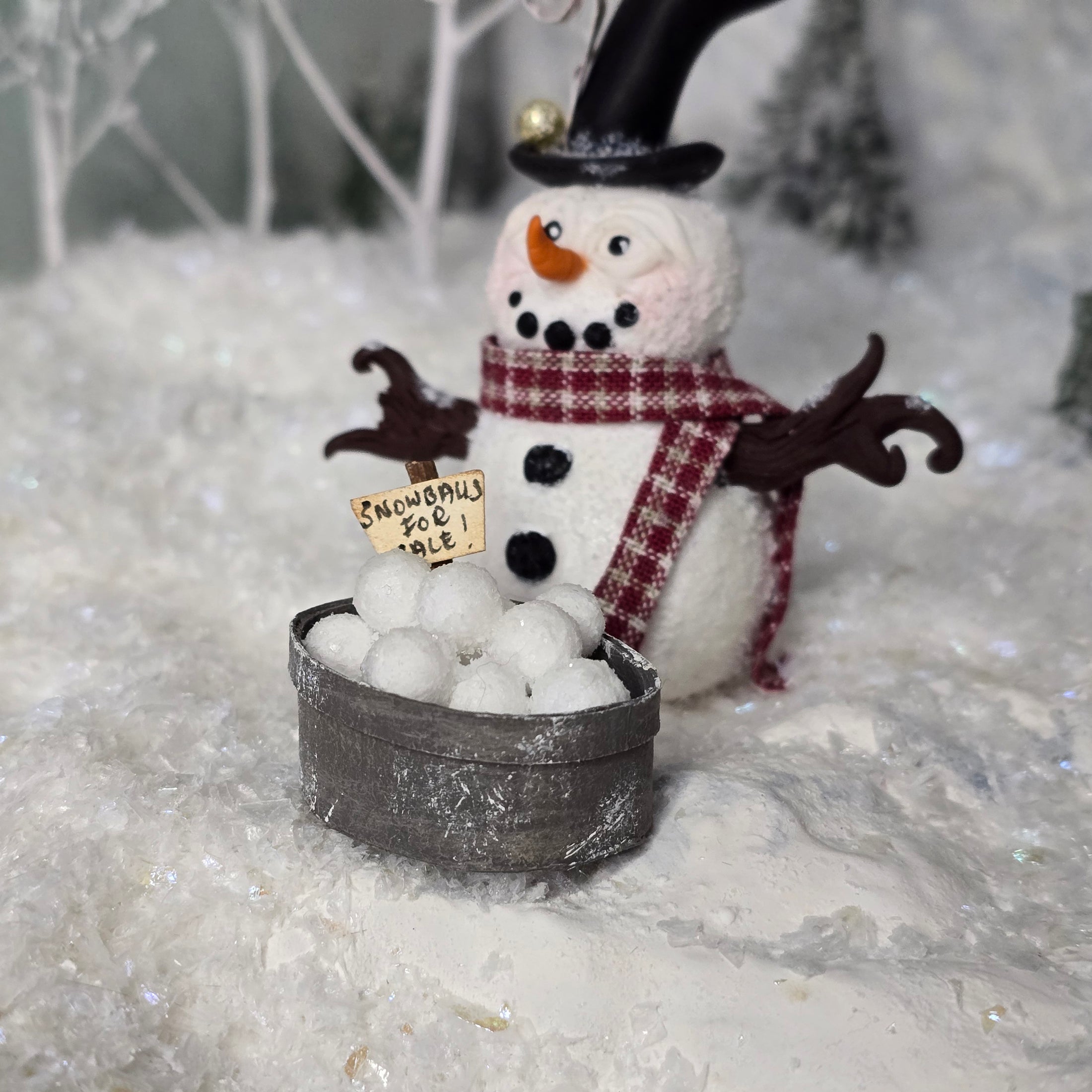Decorative snowman figurine with a sign in a snowy setting