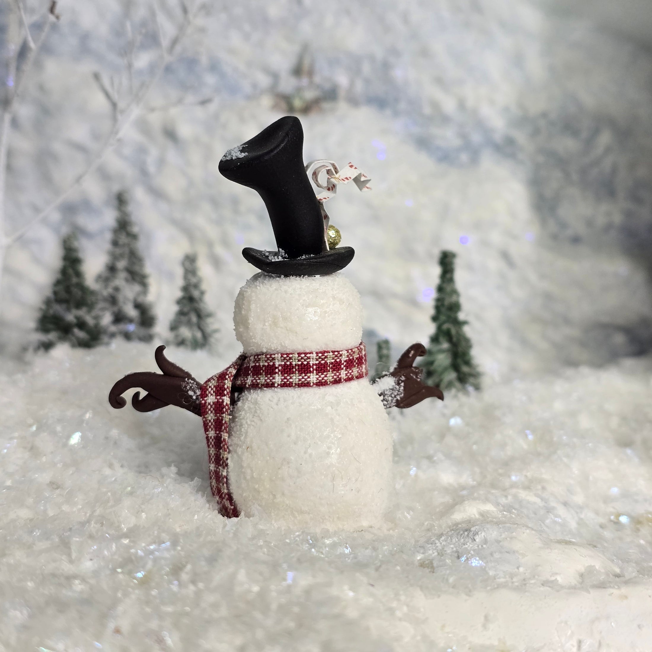 Decorative snowman miniature with a top hat and scarf against a snowy background