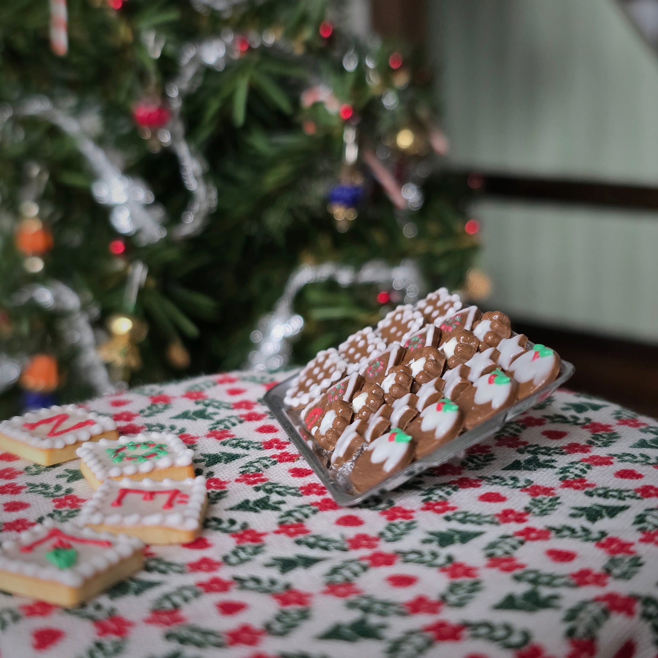 Decorative cookies on a festive tablecloth with a Christmas tree in the background