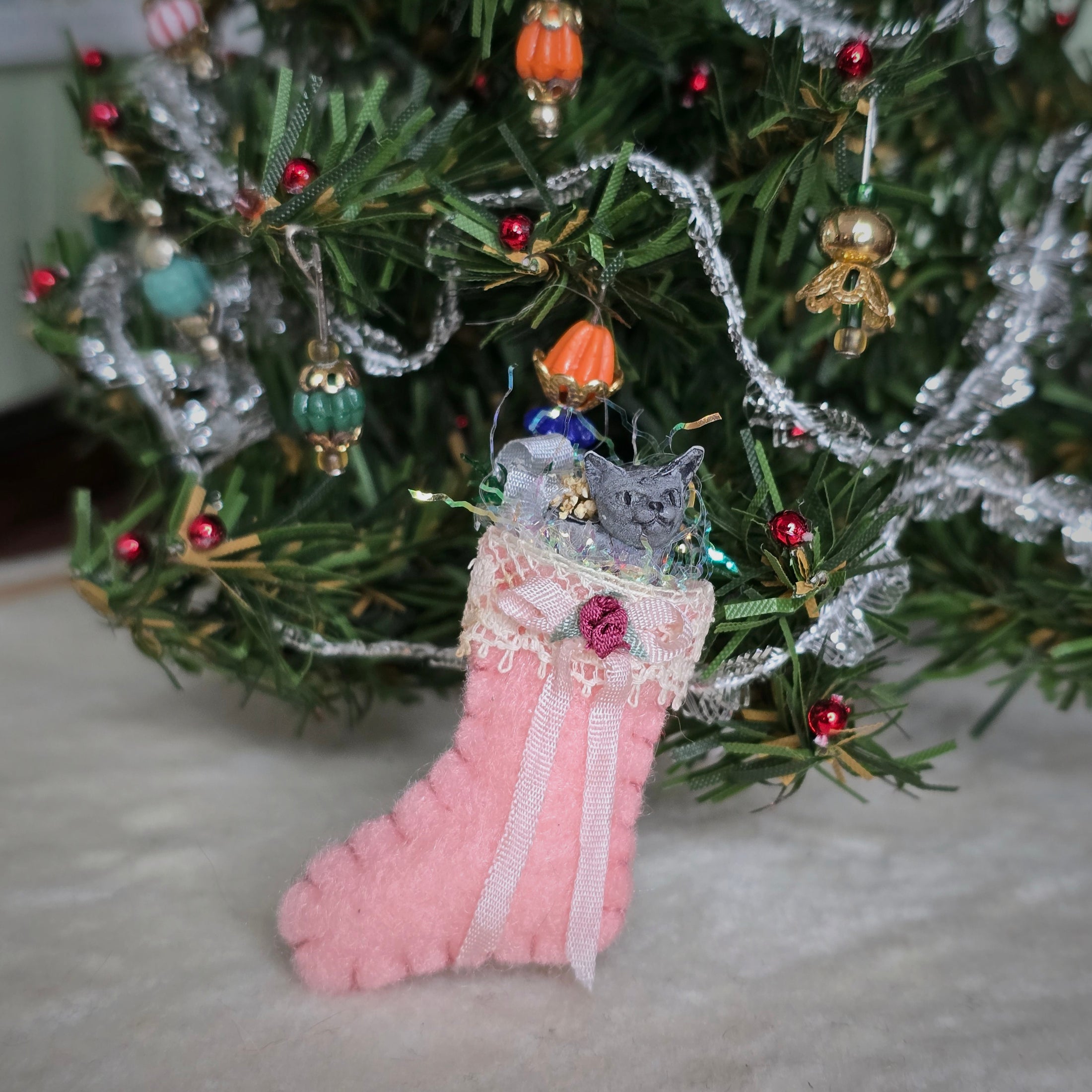 filled miniature Decorative pink stocking in front of a christmas tree