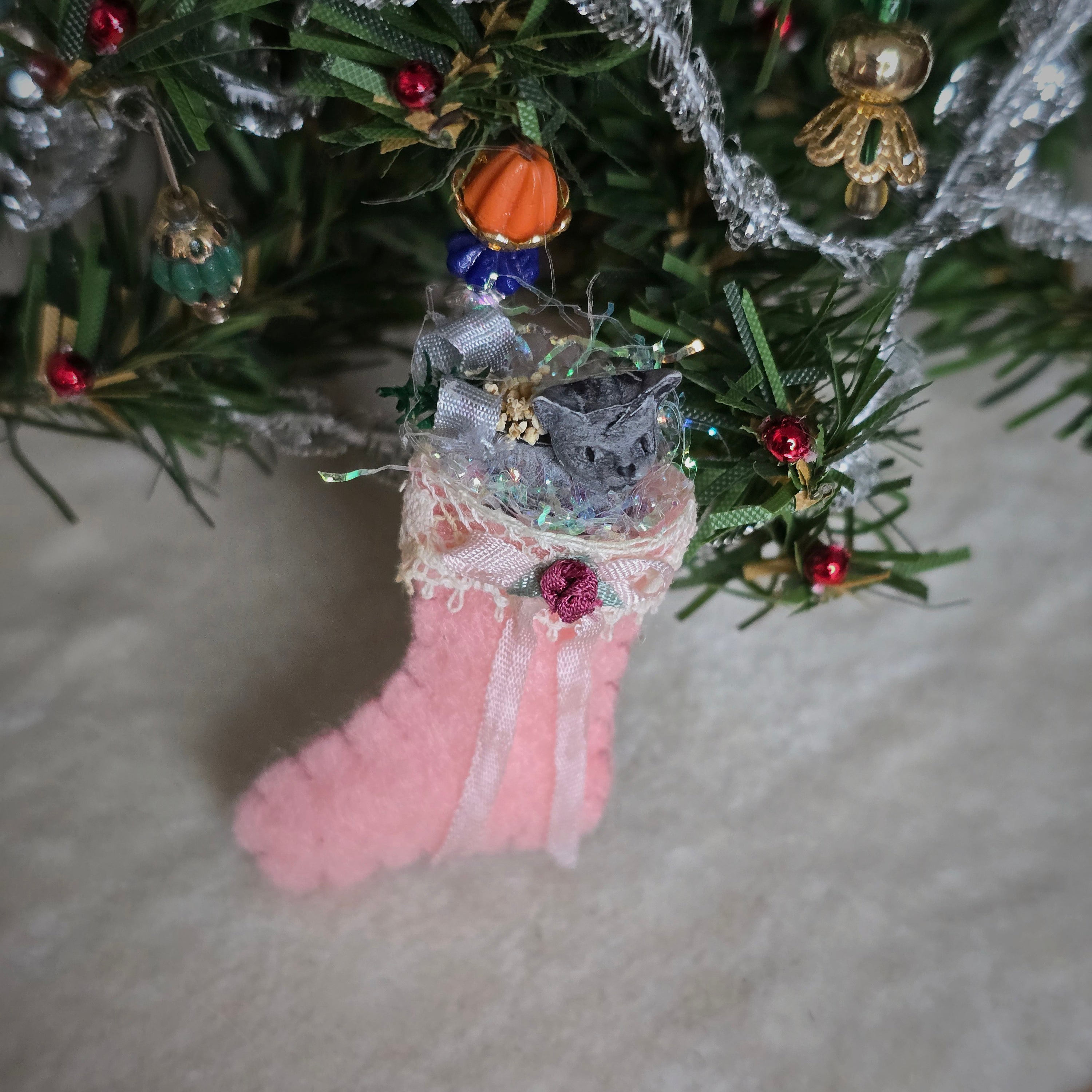 filled miniature Decorative pink stocking in front of a christmas tree