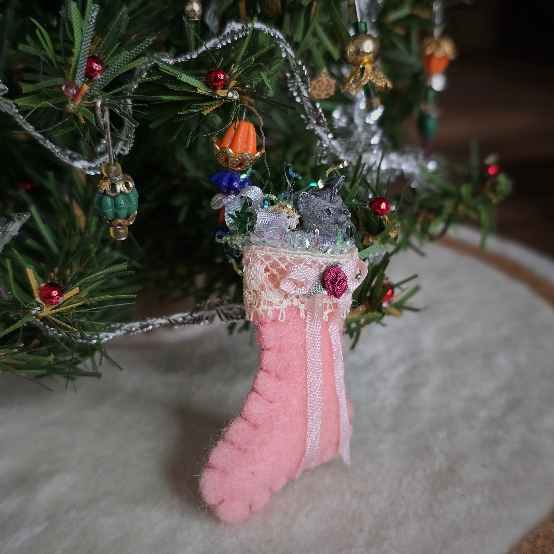 filled miniature Decorative pink stocking in front of a christmas tree