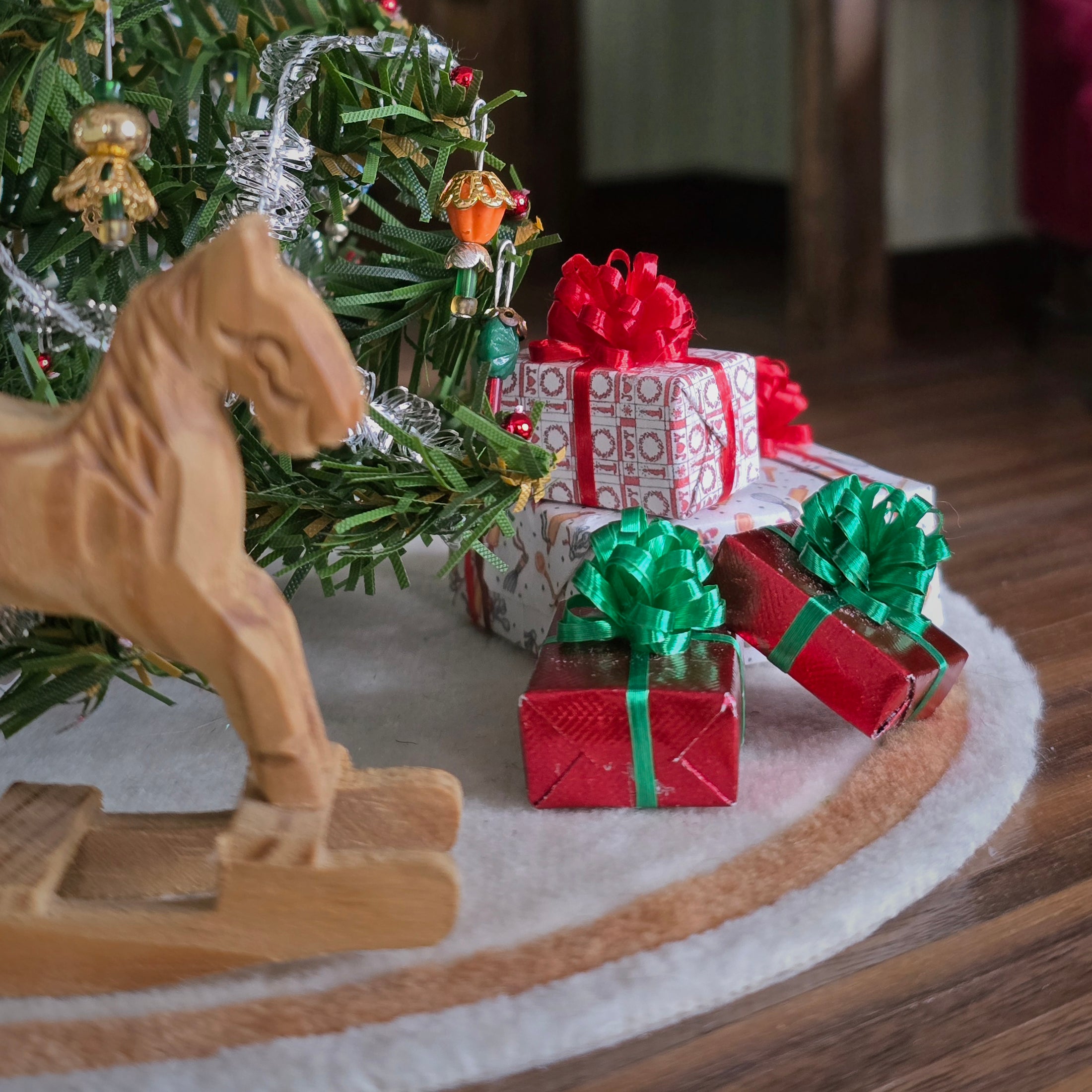 four miniature dollhouse gifts tucked underneath a christmas tree!