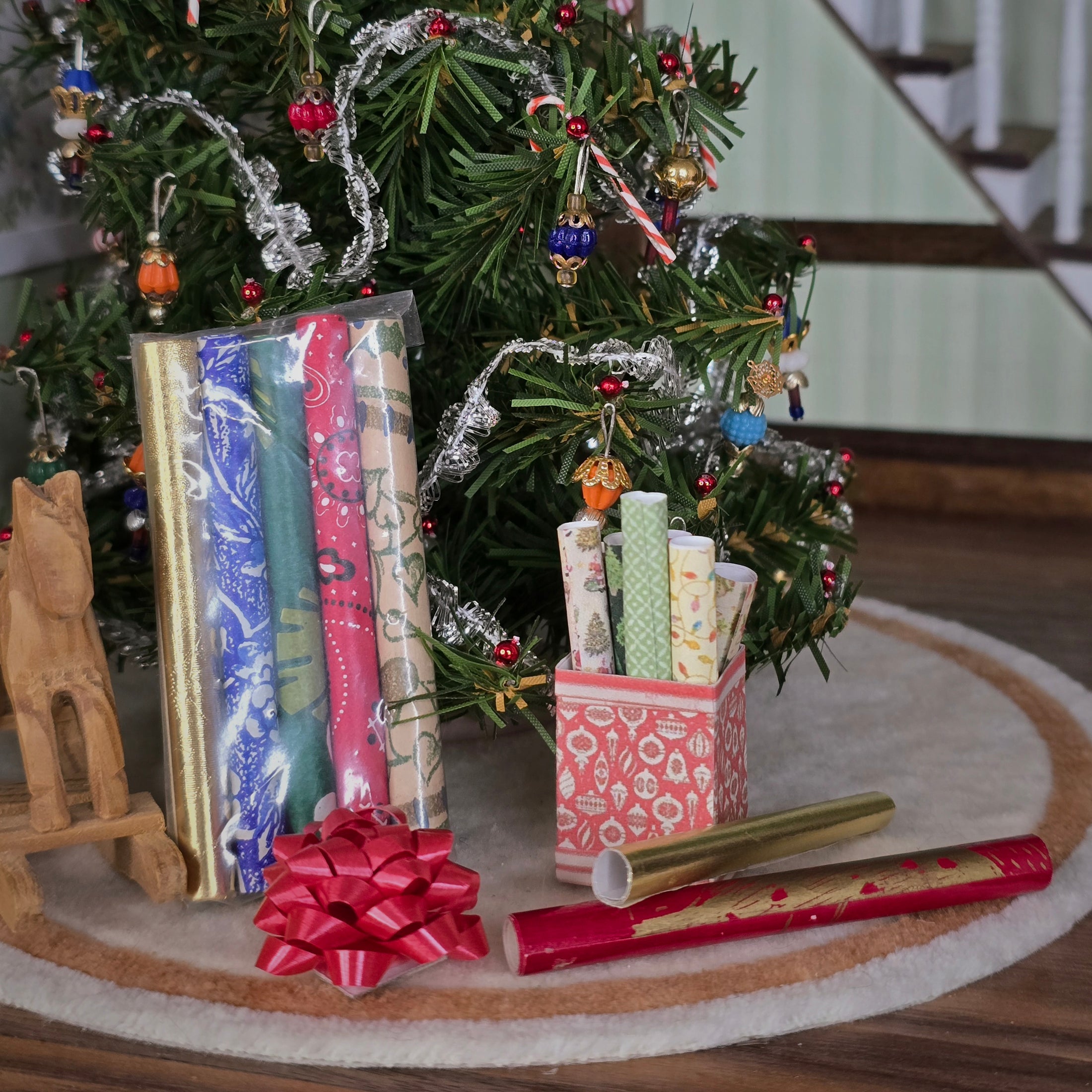 Gift wrap with ribbons and bow in front of a decorated Christmas tree.