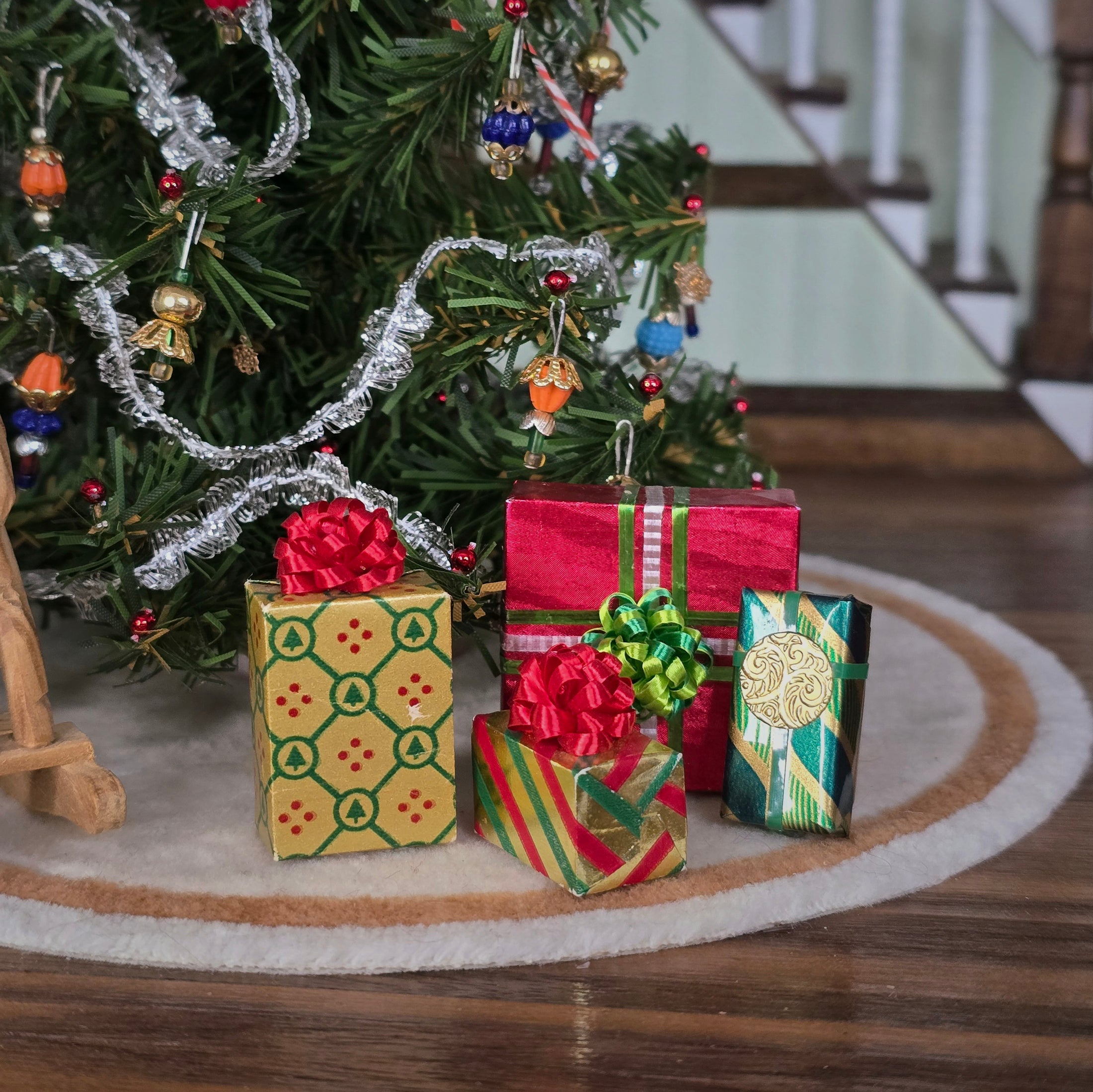 Dollhouse miniature Decorative Christmas scene with a small Christmas tree and presents on a wooden floor. 