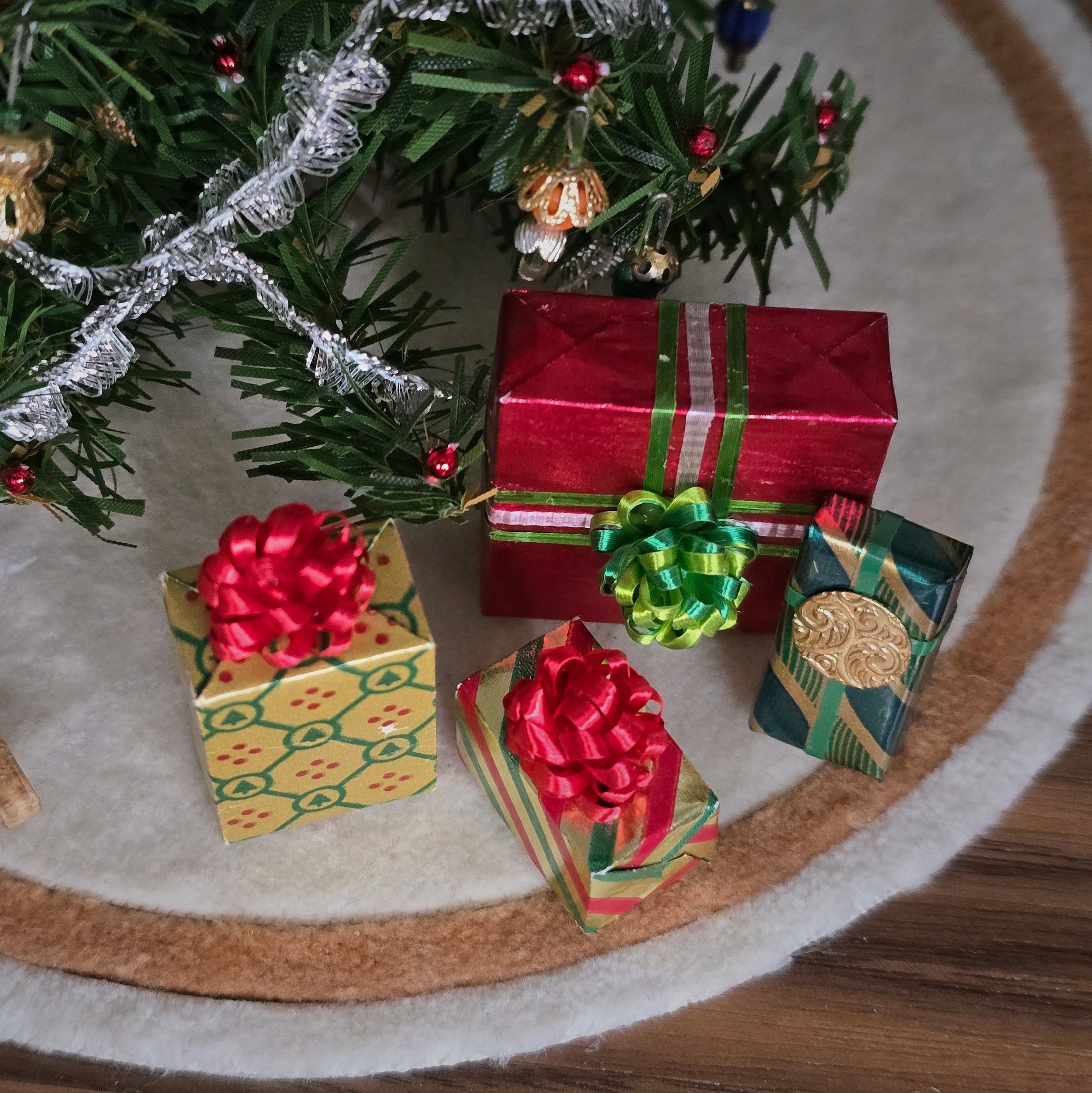 Dollhouse miniature Decorative Christmas scene with small gift boxes and a tree on a textured surface.