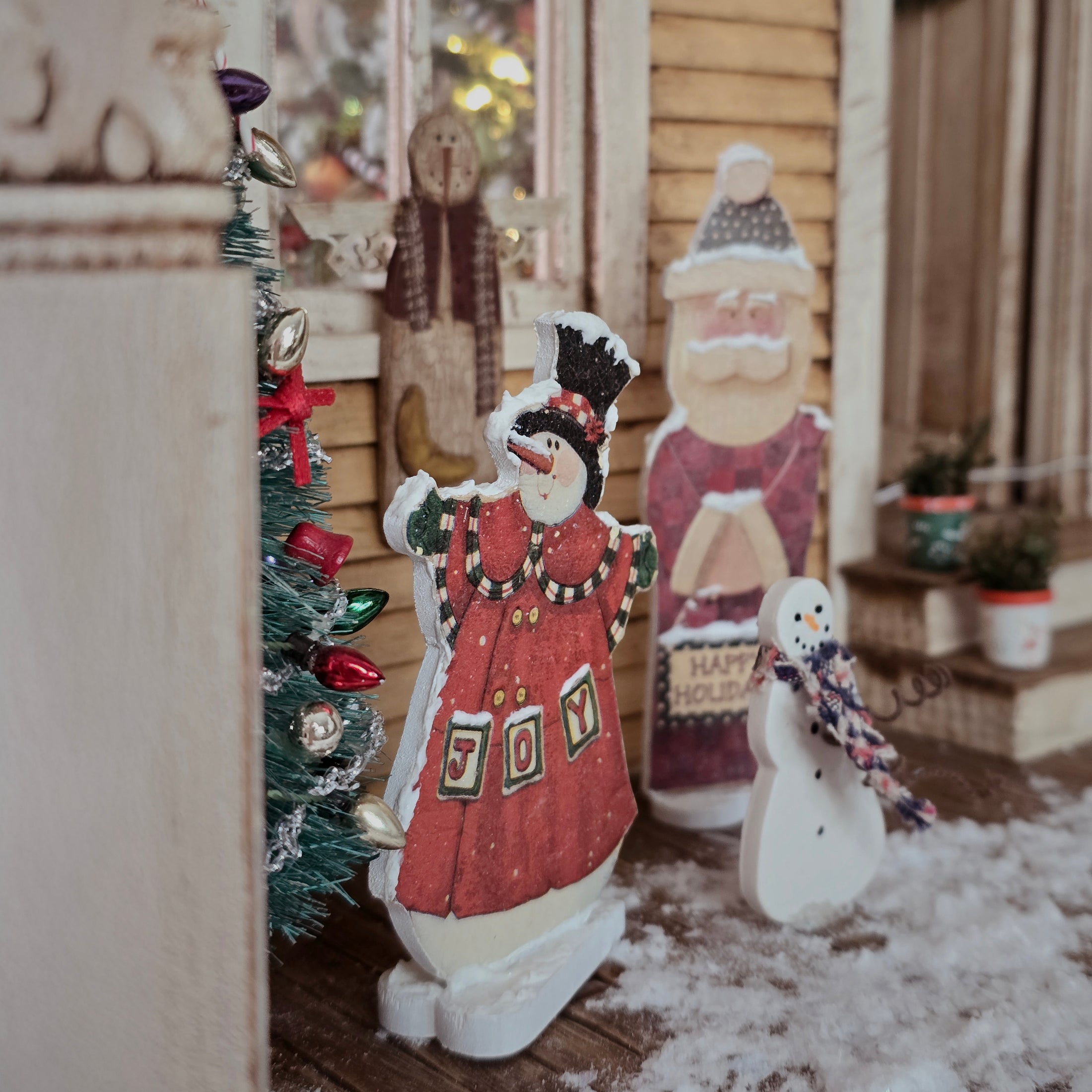 Decorative snowmen and Christmas tree in a cozy porch setting. Dollhouse miniatures.