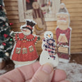 Load image into Gallery viewer, Hand holding a Dollhouse miniature decorative snowman with scarf in front of Christmas decorations.
