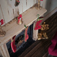 Load image into Gallery viewer, Decorative miniature Christmas stockings hanging on a mantelpiece with gold bells.
