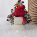 Load image into Gallery viewer, Back view of a small snowman with a red hat and scarf in front of a Christmas tree.
