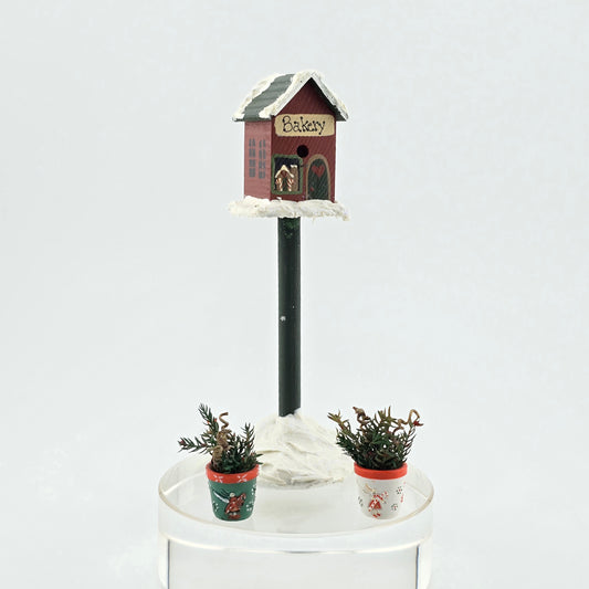 miniature dollhouse Christmas bakery birdhouse and potted plant set on white background