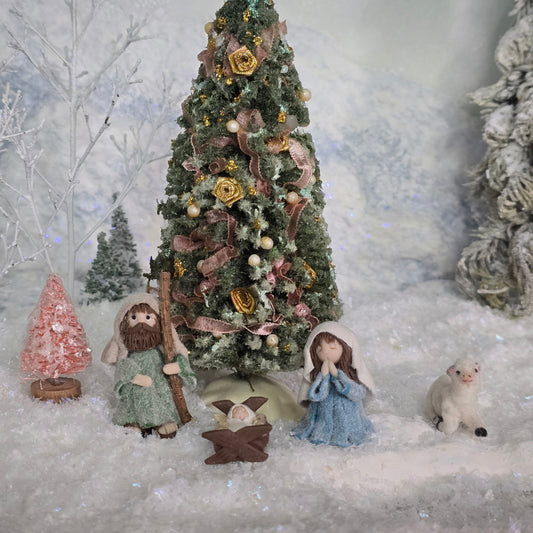 Decorative Christmas scene with trees, nativity figures and animals in a snowy setting. miniature dollhouse.