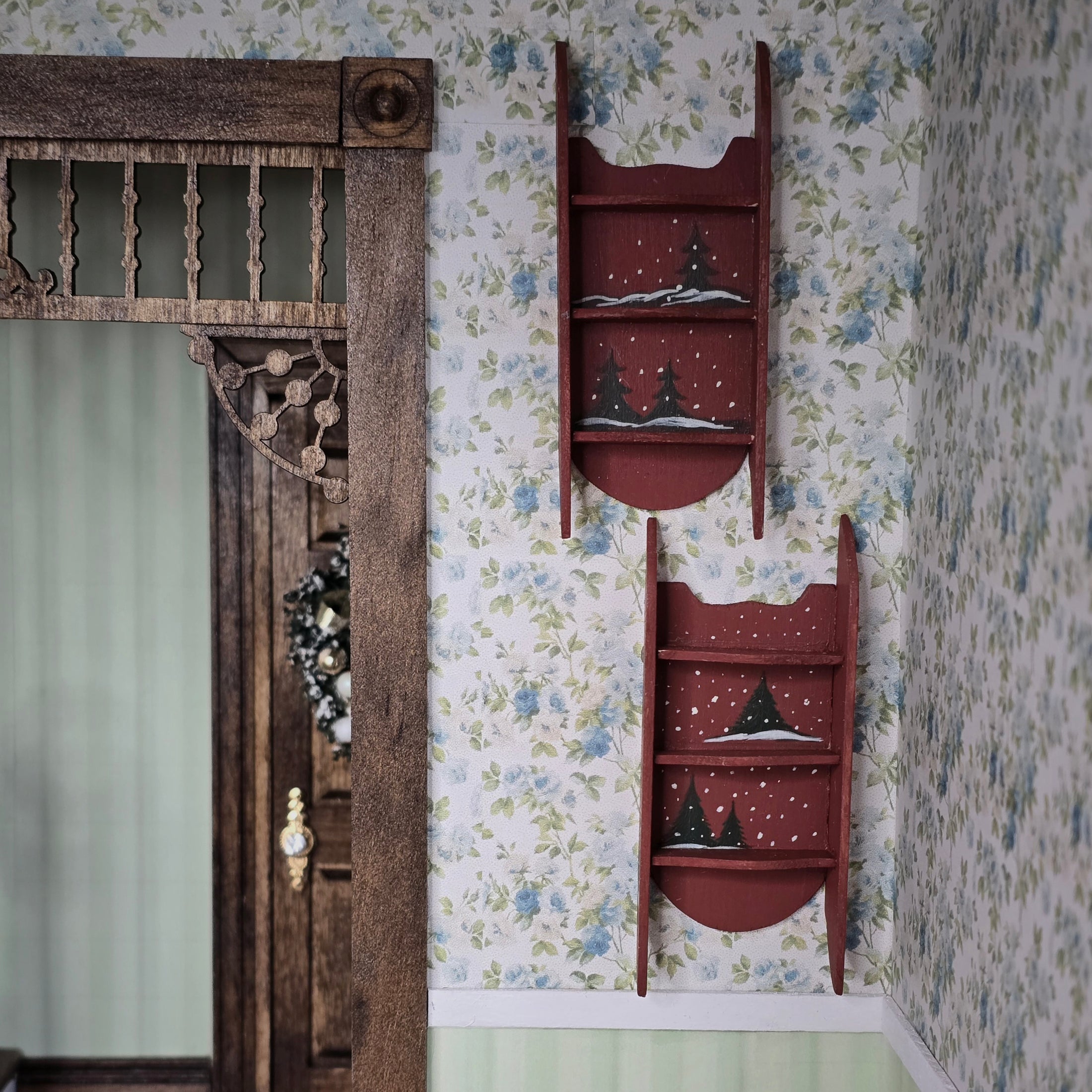 pair of Wooden ladder shelves with decorative Christmas trees against a floral wallpapered wall.