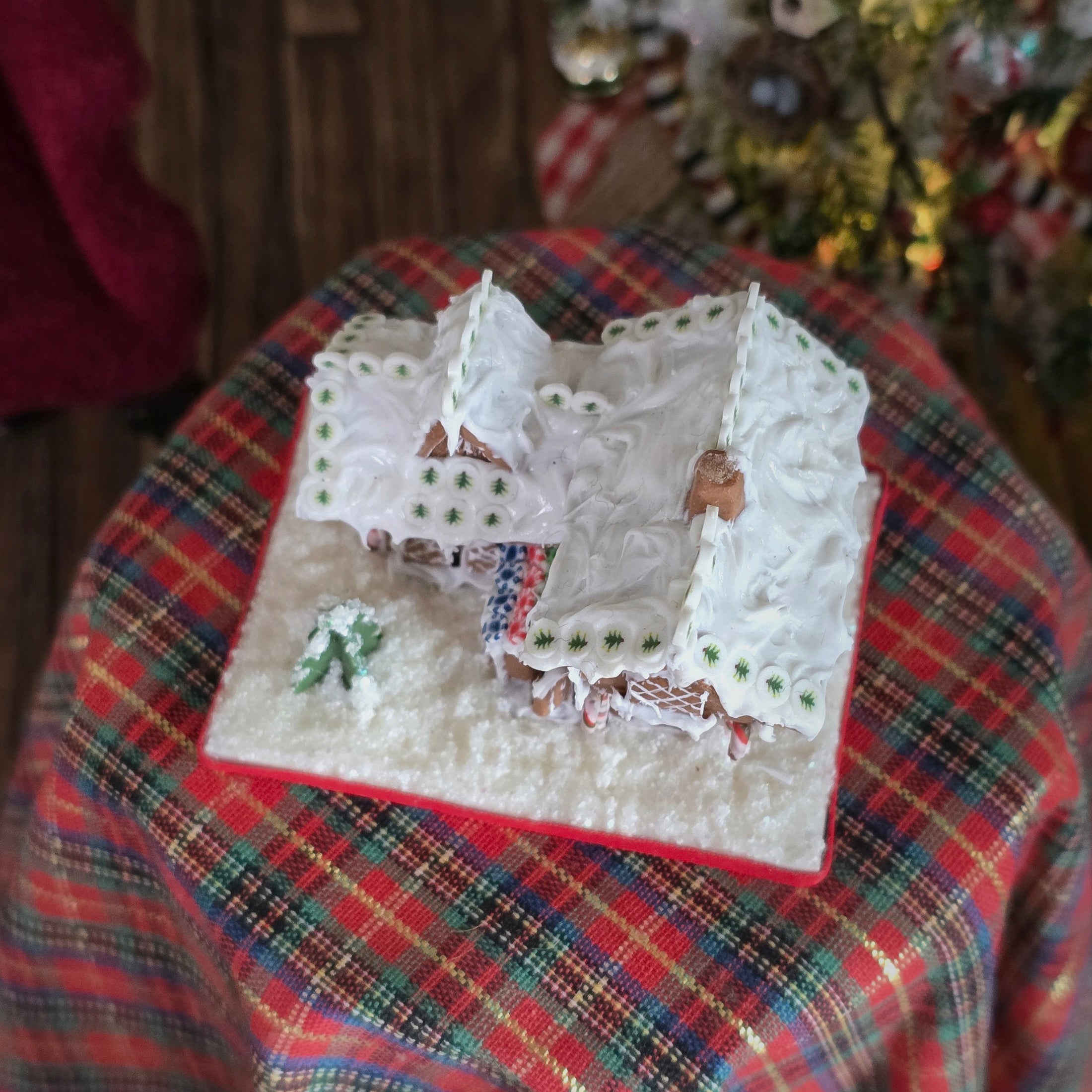 Decorative gingerbread house on a plaid surface with a blurred background, top view