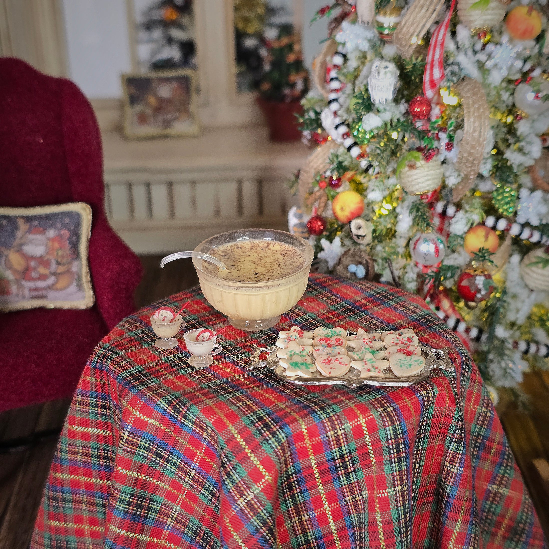 Decorative table setting with a tartan tablecloth, bowl, and cookies in front of a Christmas tree.