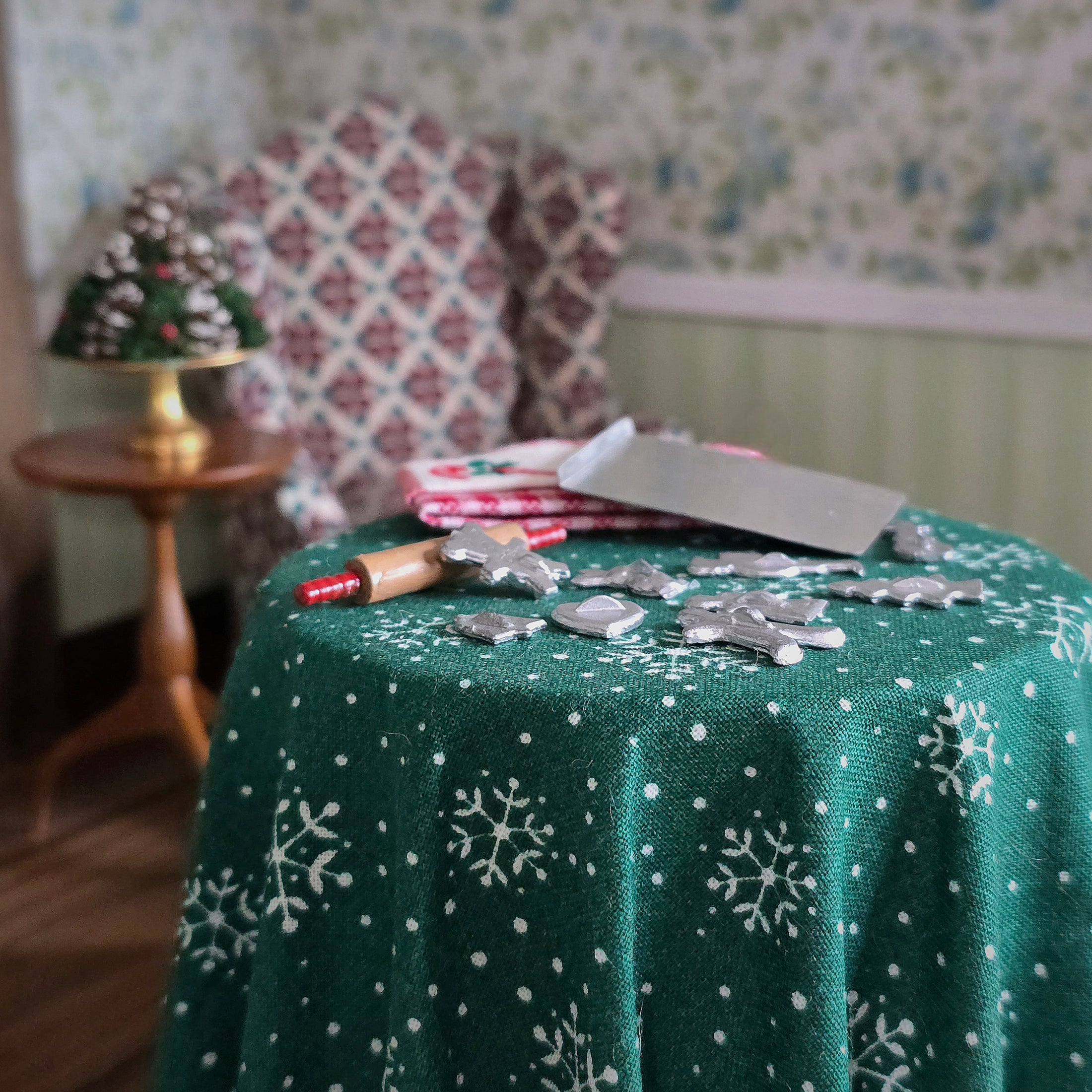 close-up shot of Green tablecloth with snowflake patterns on a table, with decorative items in the background.