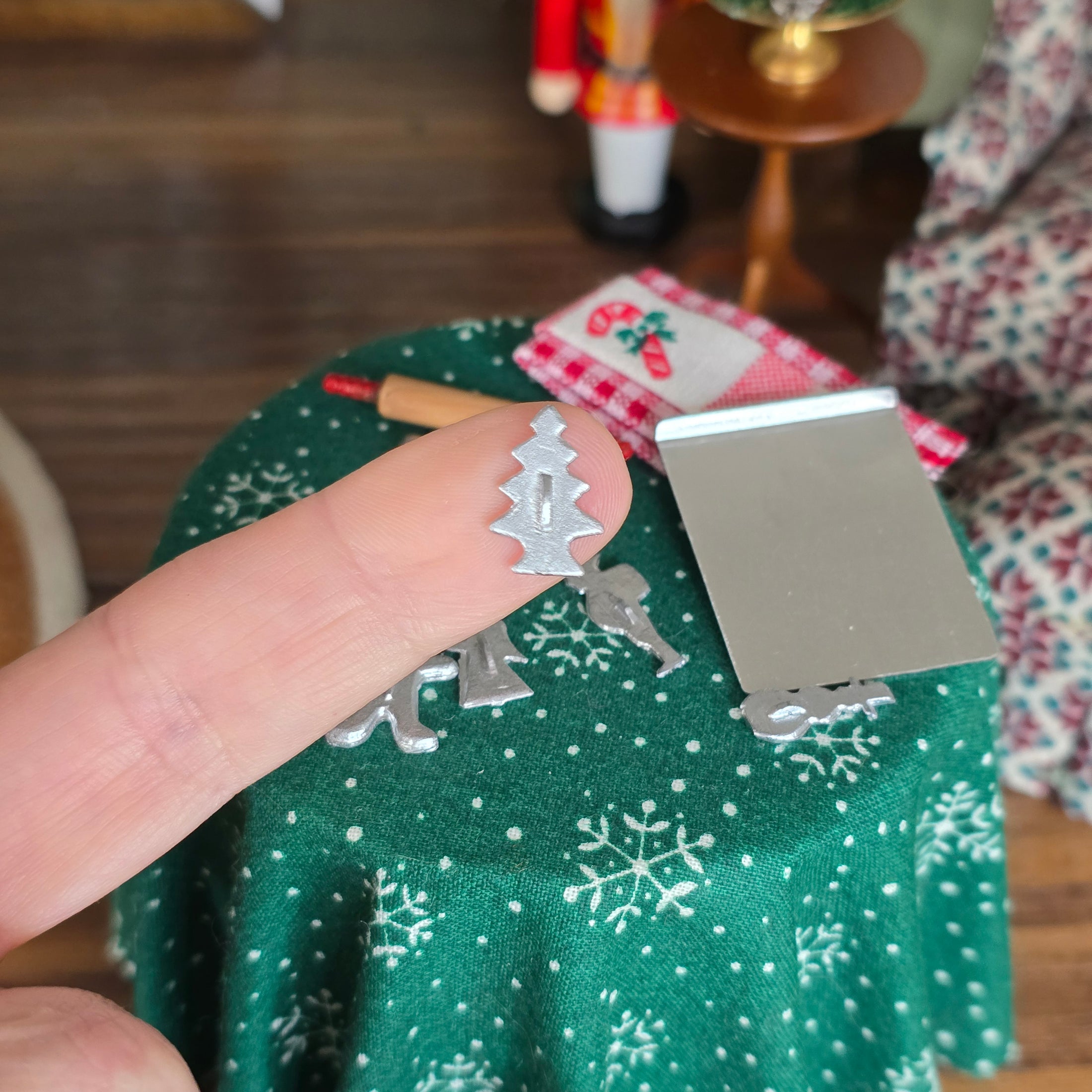 Metal Christmas tree-shaped cookie cutter on a finger for a close-up.