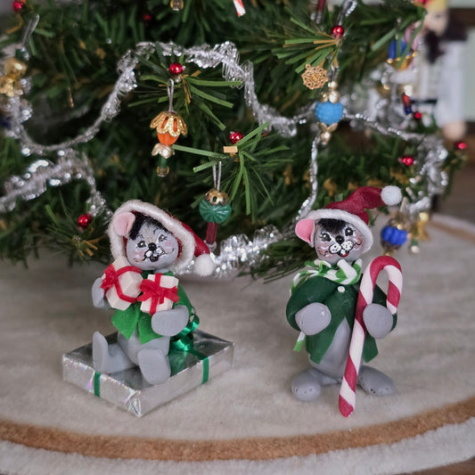 Two Christmas-themed Annalee style mice figurines in front of a decorated tree.