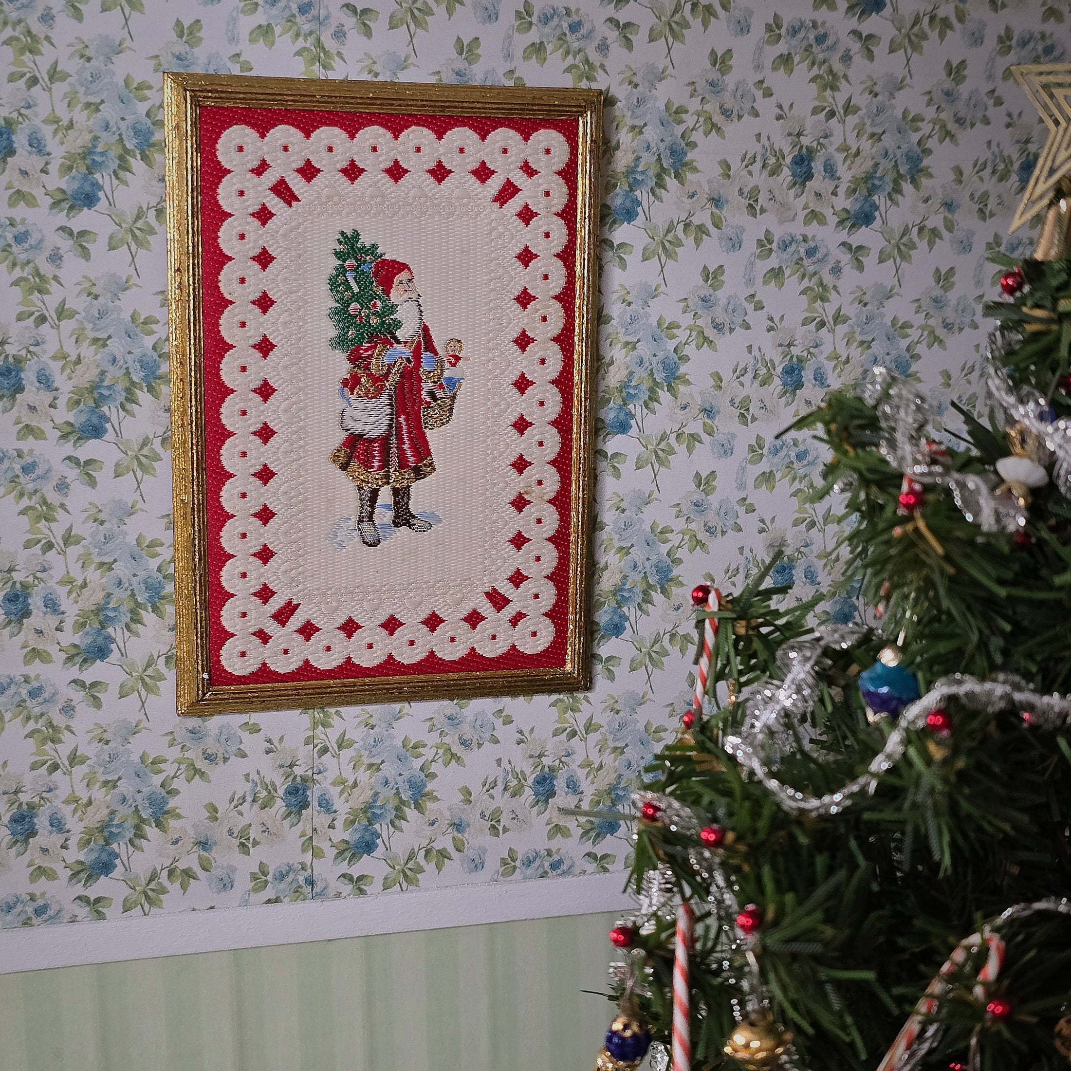 Framed miniature embroidered Victorian Santa Claus, hanging on wallpapered wall
