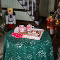 Load image into Gallery viewer, Miniature Christmas scene with a table, snowflake-patterned cloth, and decorative items.
