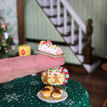 Load image into Gallery viewer, Miniature cake held by a hand with a festive background
