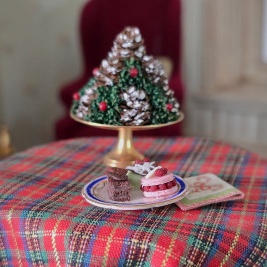 Decorative Christmas tree and small cakes on a plaid tablecloth