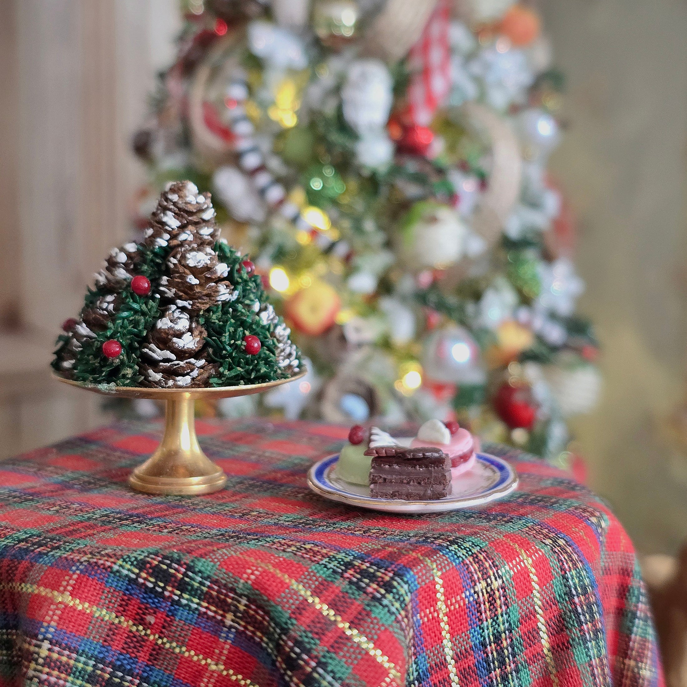 Decorative Christmas tree with pine cones and small cakes on a plate