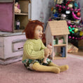 Load image into Gallery viewer, Catherine Muniere doll in a sweater holding a toy in a room with toys and furniture.
