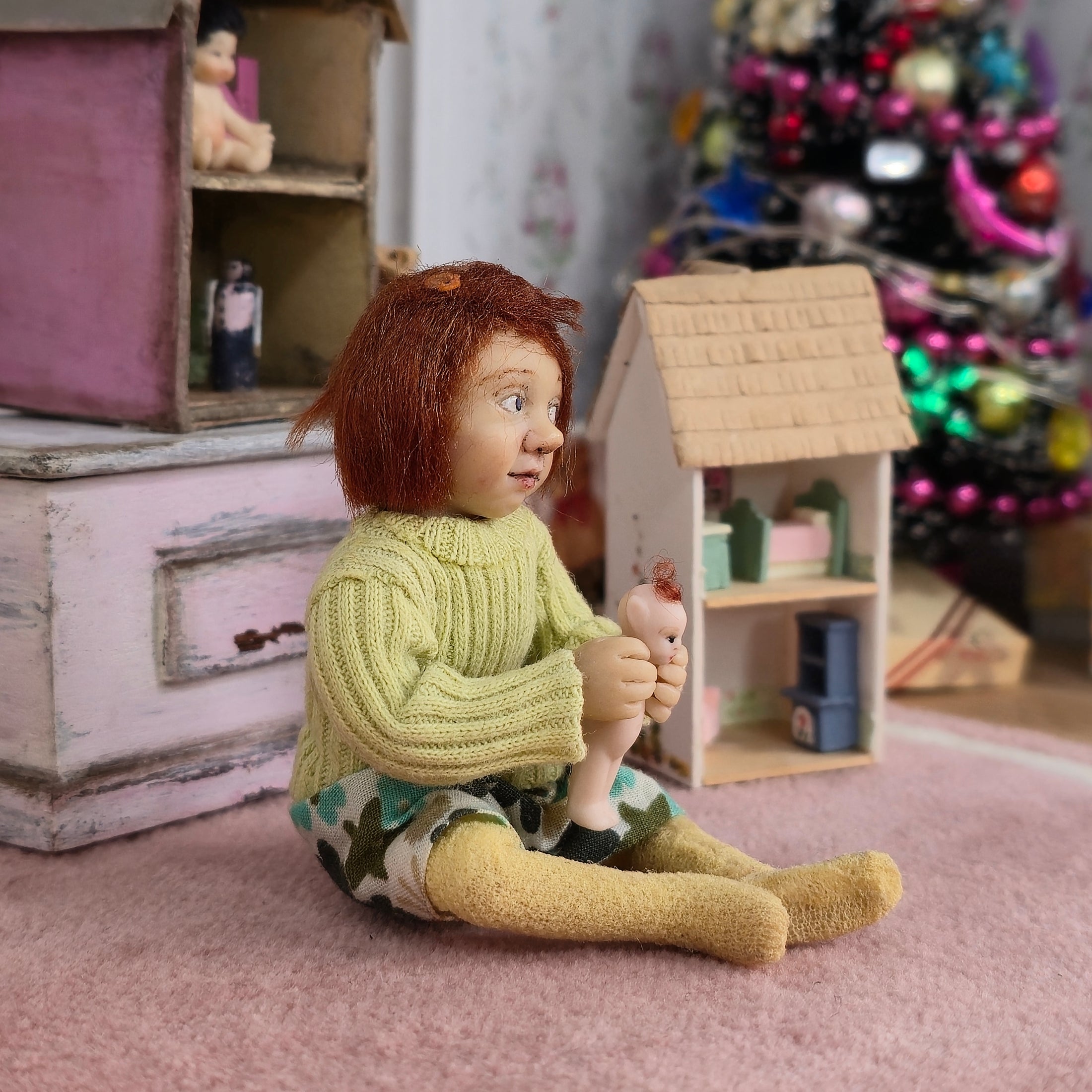 Catherine Muniere doll in a sweater holding a toy in a room with toys and furniture.
